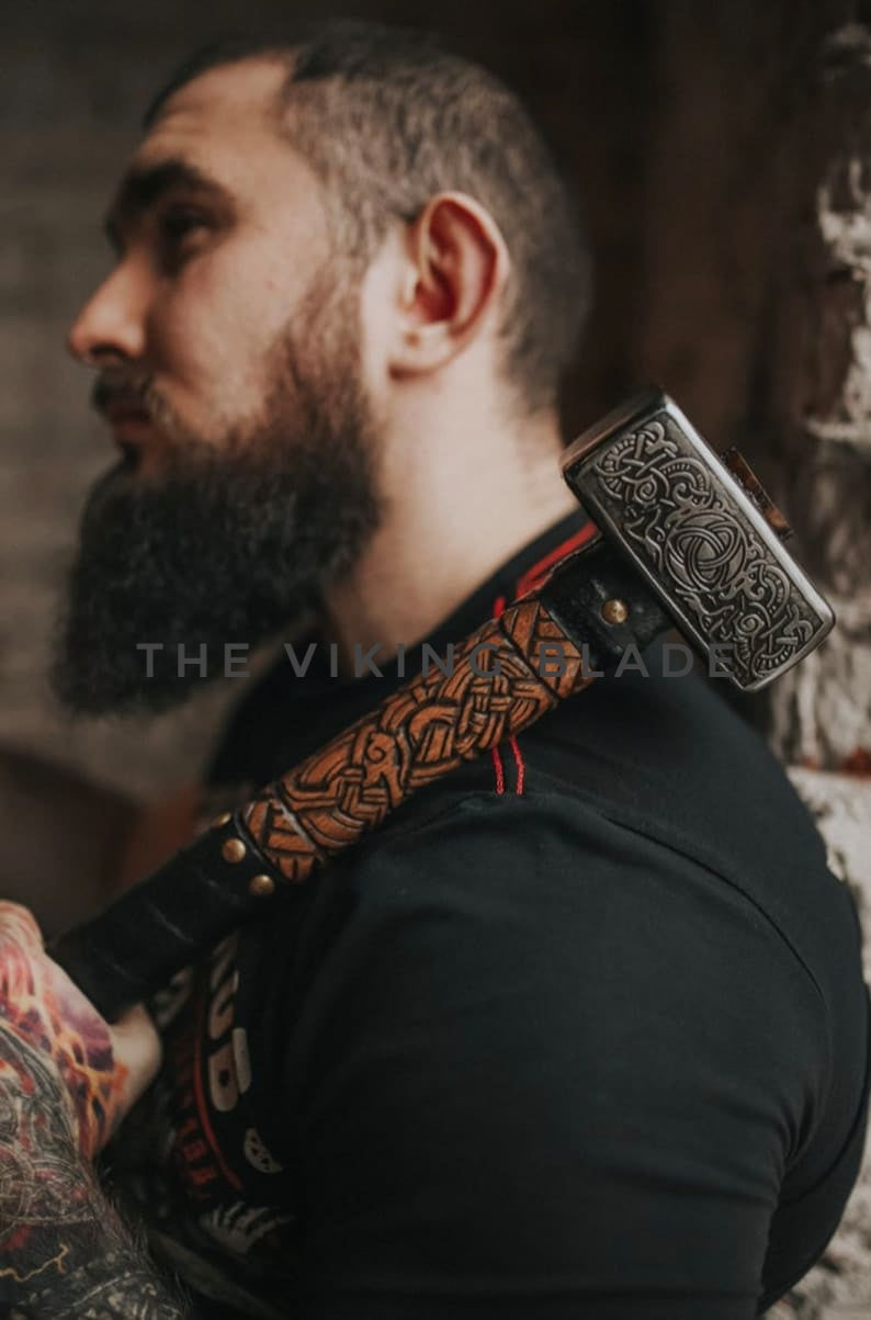 Man holding a decorative axe with 'The Viking Blade' branding.
