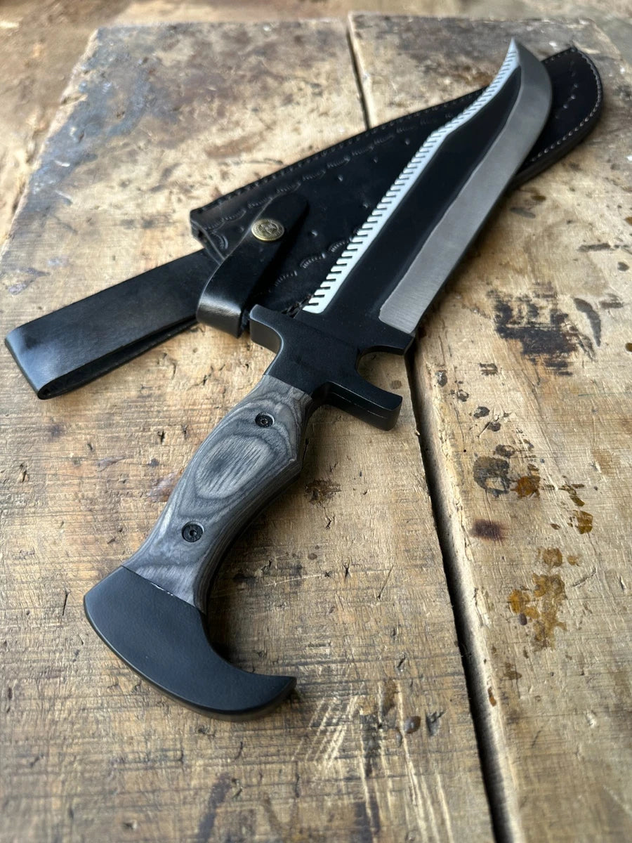 A fixed-blade knife with a black handle and a serrated silver blade, shown alongside a black sheath on a rustic wooden surface.