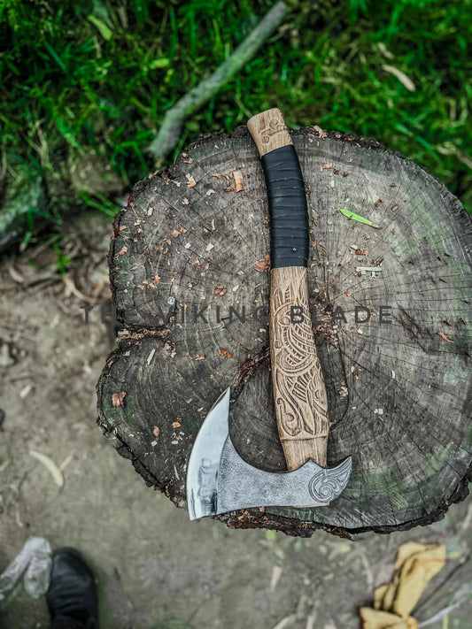 Wooden-handled axe with engraved design on a tree stump, brand 'Vikings Blades' visible