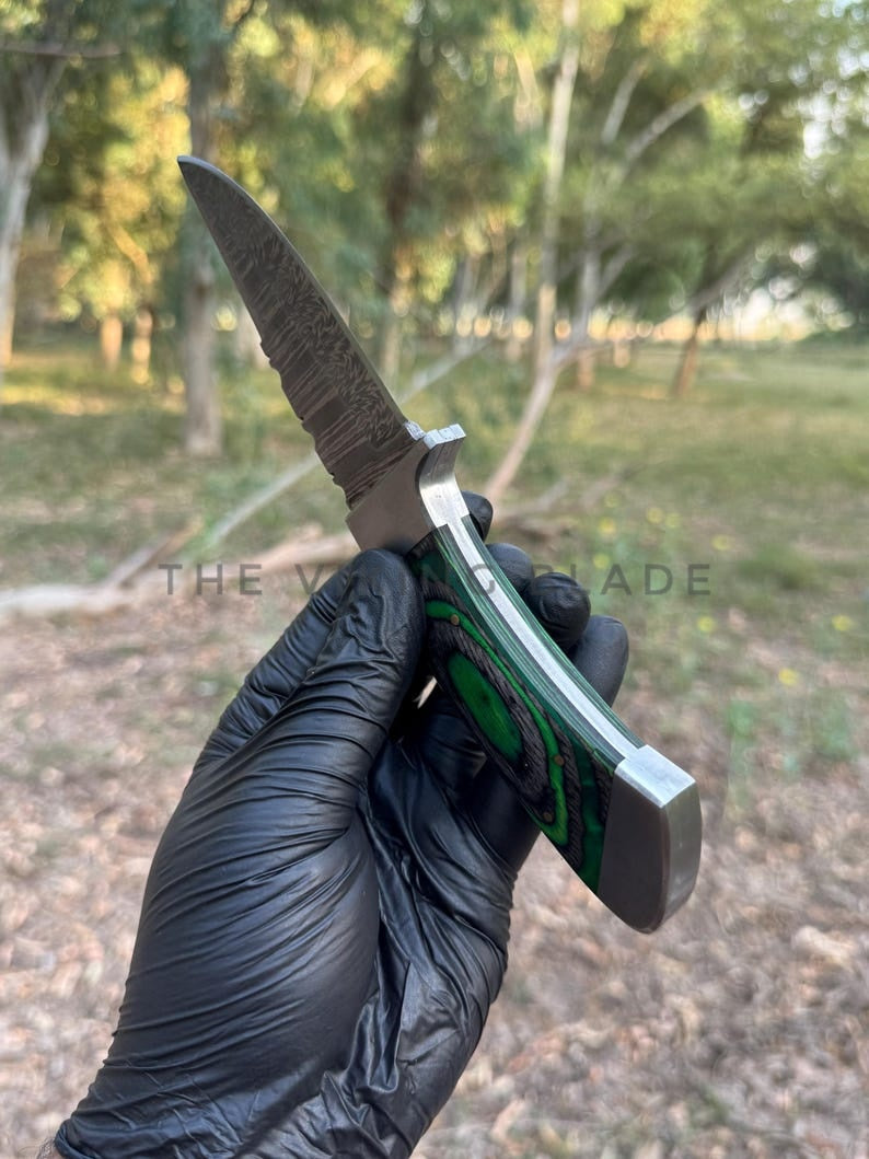Knife held by a gloved hand with a blurred natural background