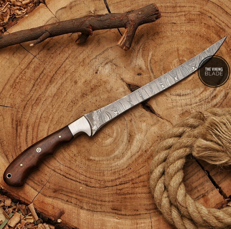 A Damascus boning knife with a striped pattern blade and a brown leather sheath, displayed on a wooden cross-section.