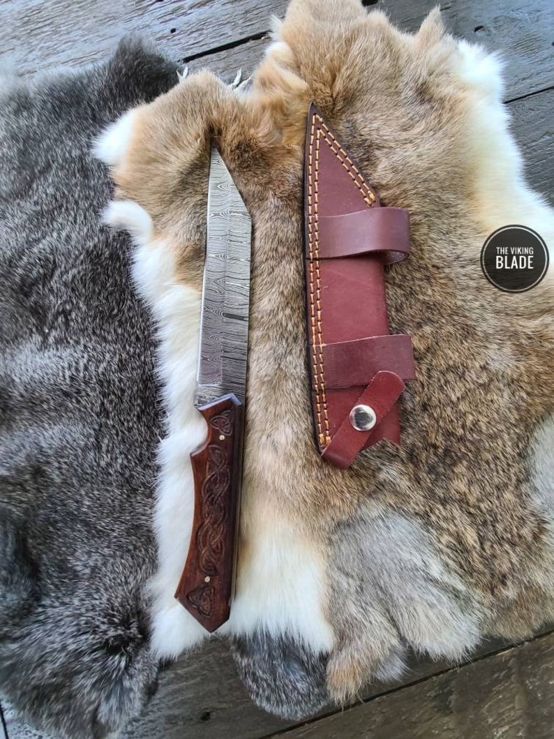 Close-up of the Damascus blade and engraved walnut handle on a handmade Seax knife.