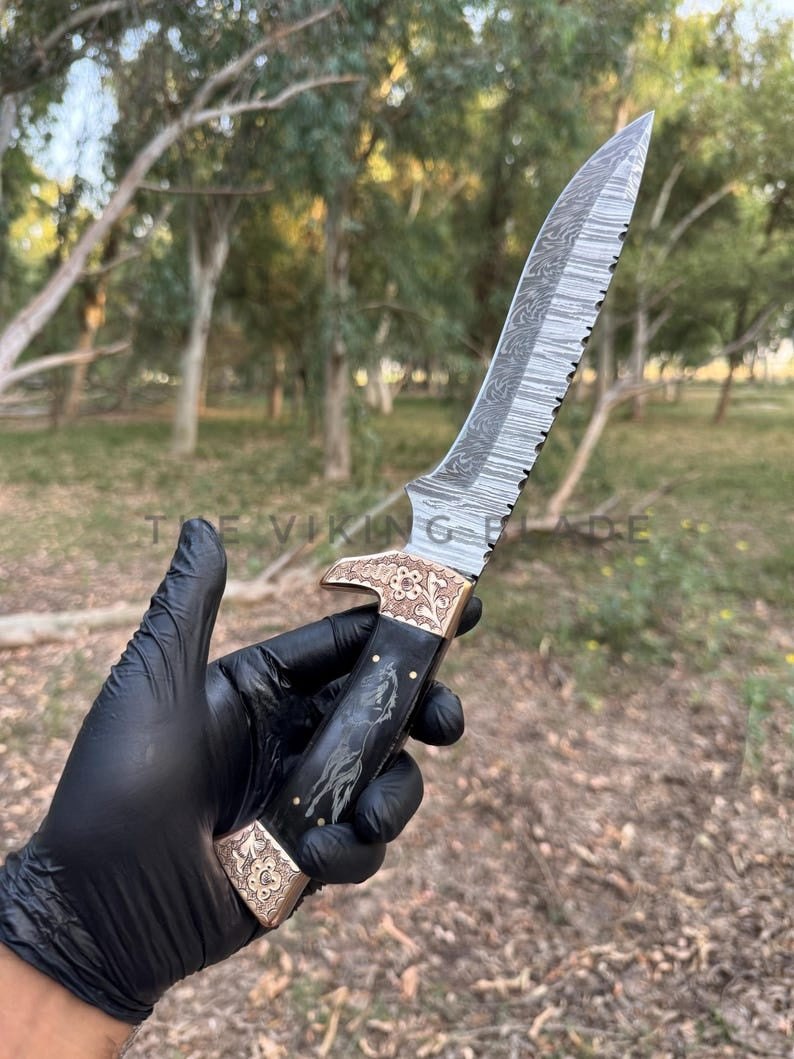 Decorative knife held by a person wearing a black glove in an outdoor setting.