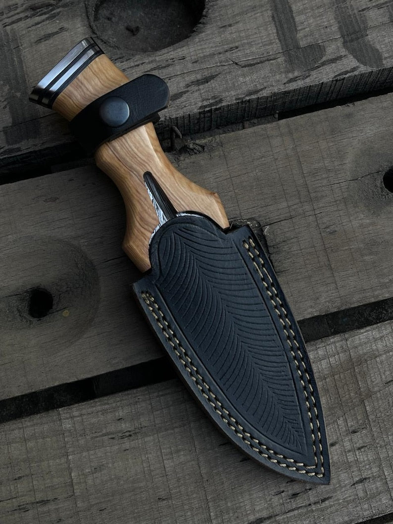 Knife with wooden handle and black sheath on a wooden surface