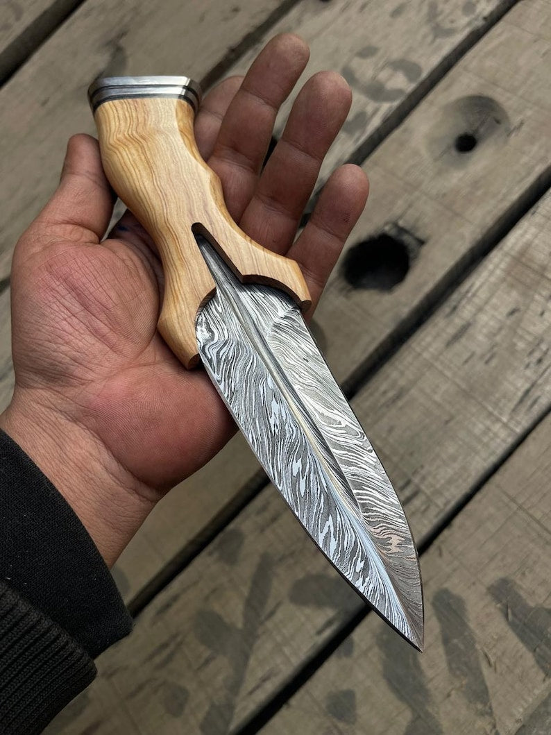 Hand holding a knife with a wooden handle on a wooden surface