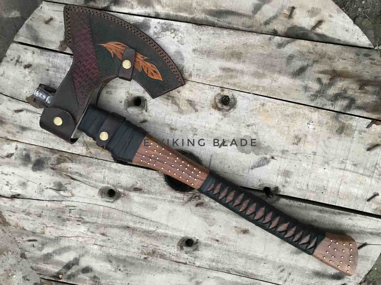 Decorative axe with leather sheath on a wooden surface, branded 'KING BLADE'.