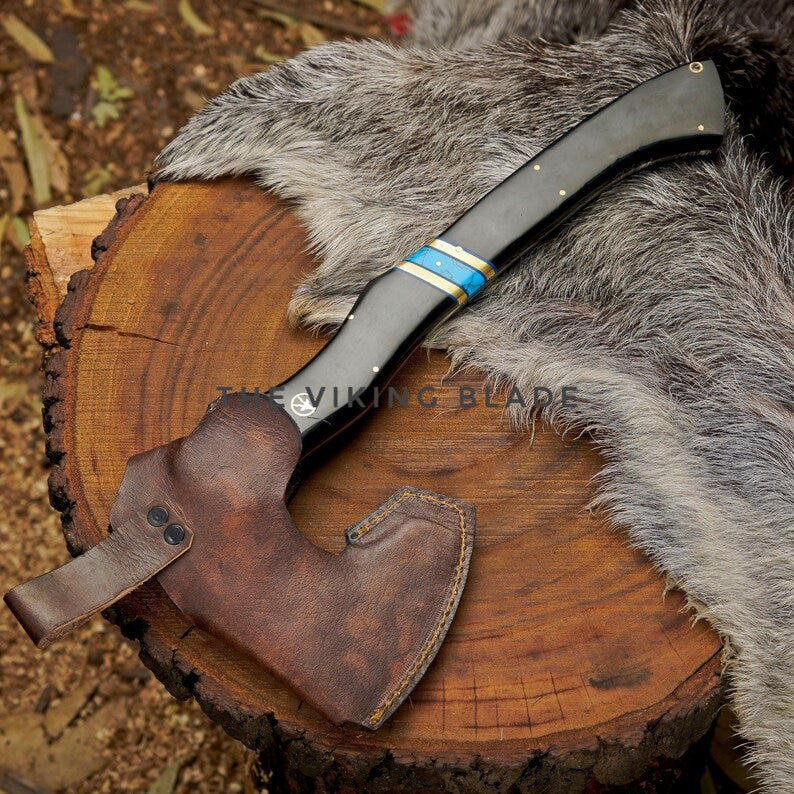 Viking-style axe with leather sheath on a wooden stump and fur background, featuring 'The Viking Blade' branding.