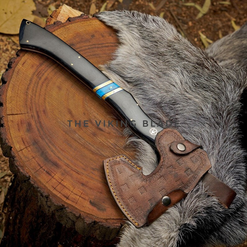 Forked axe with leather sheath on a wooden stump and fur background, branded 'The Viking Blade'.