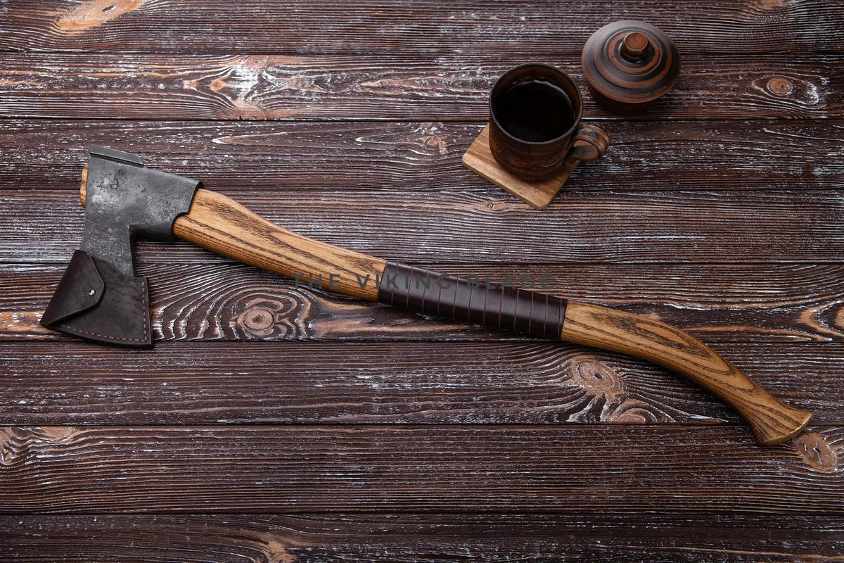 Wooden axe with leather handle on a wooden surface