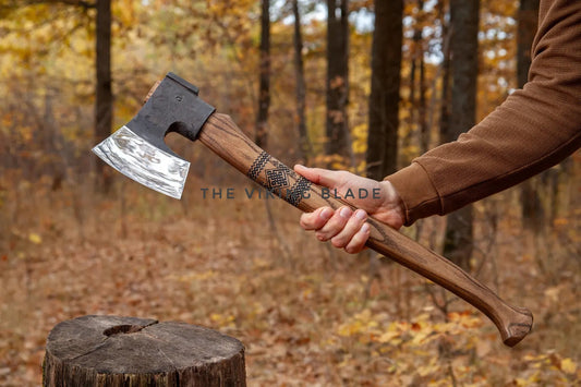 Person holding a wooden-handled axe in a forest setting