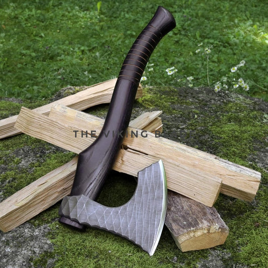 Axes with a textured blade and wooden handle on a pile of wood against a natural background