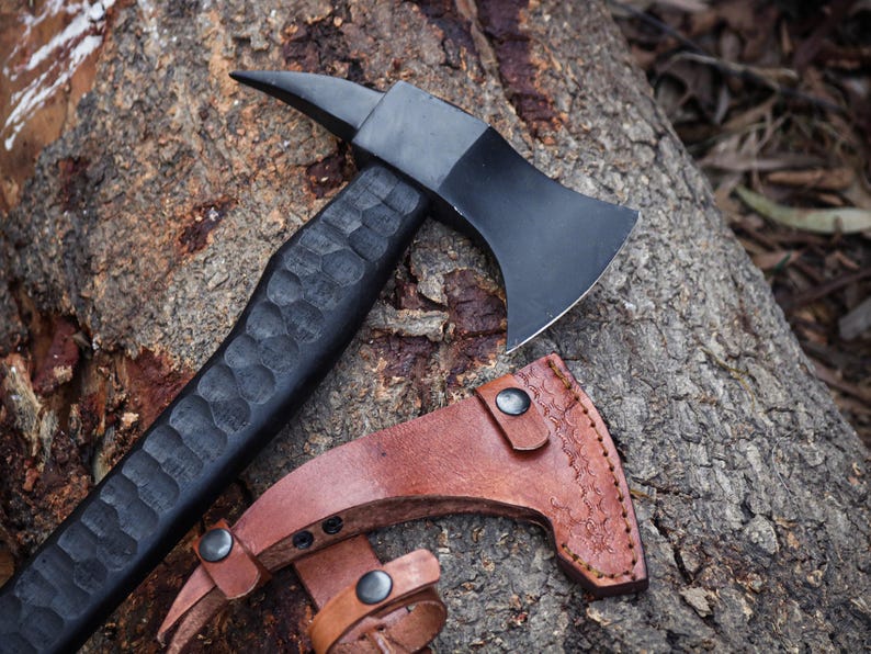 Axes with leather sheaths on a wooden surface