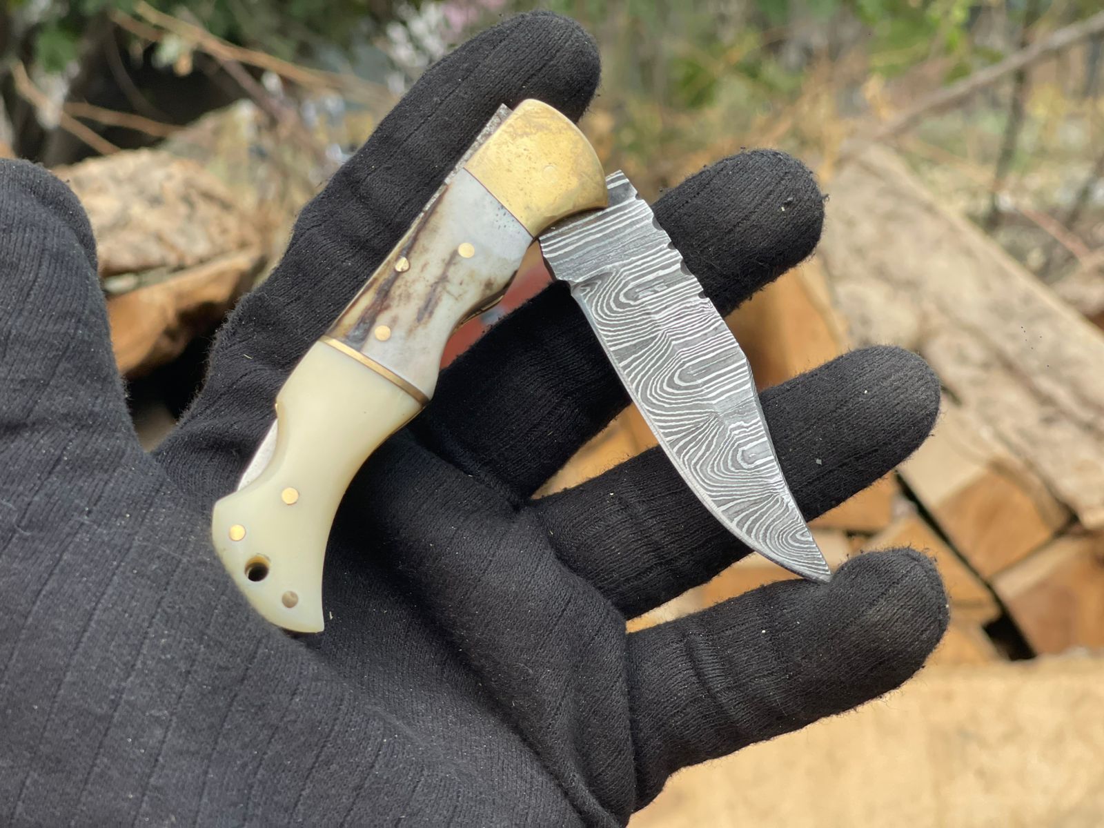 Knife with a decorative blade held by a gloved hand against a natural background
