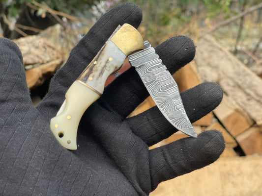 Knife with a decorative blade held by a gloved hand against a natural background