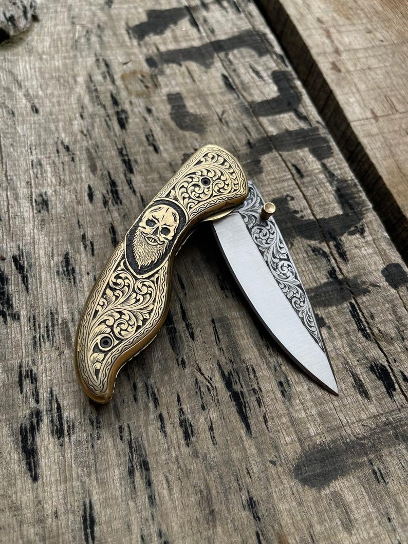 Decorative pocket knife with skull design on a wooden surface