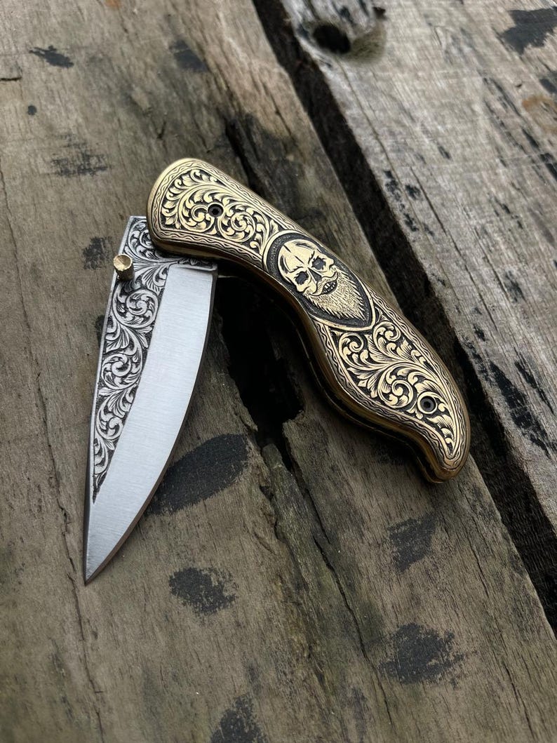 Decorative pocket knife with ornate handle on a wooden surface