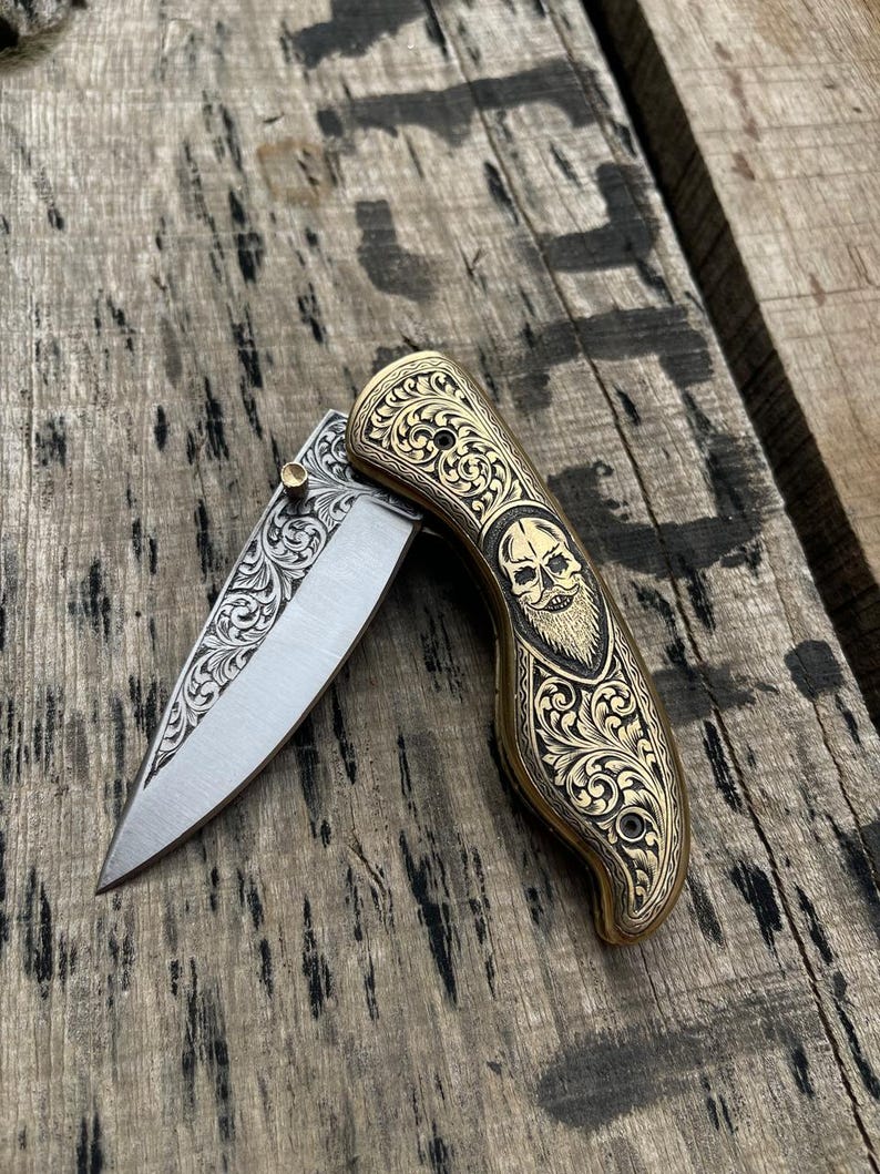Decorative folding knife with skull design on a wooden surface