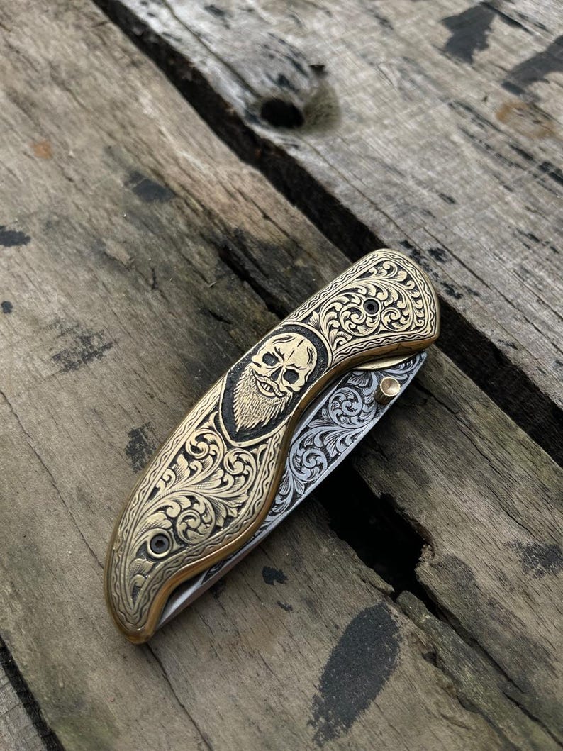 Decorative pocket knife with intricate patterns on a wooden surface