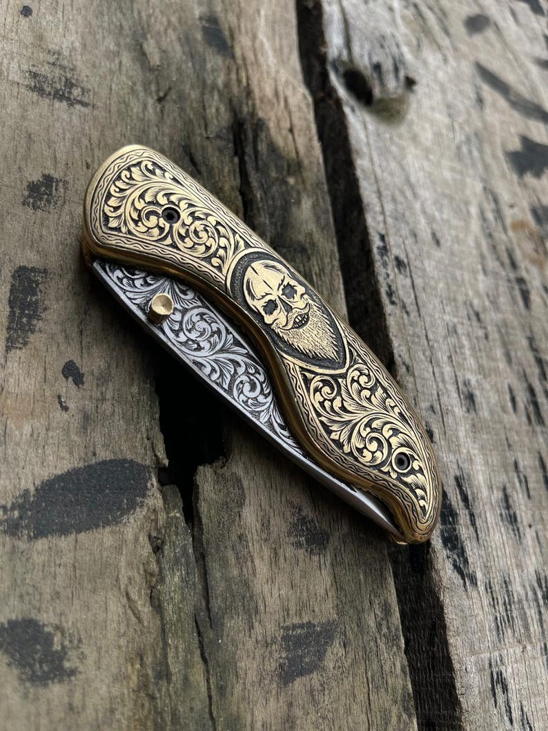 Decorative pocket knife with intricate patterns on a wooden surface