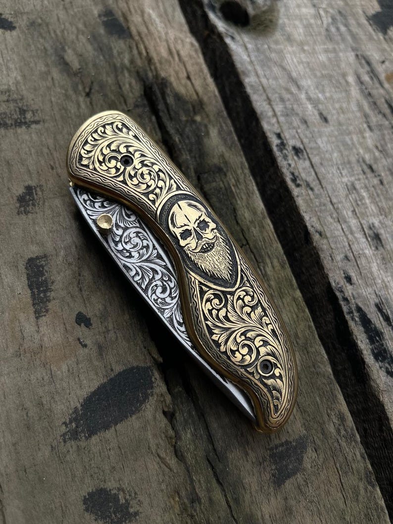 Decorative folding knife with skull design on a wooden surface