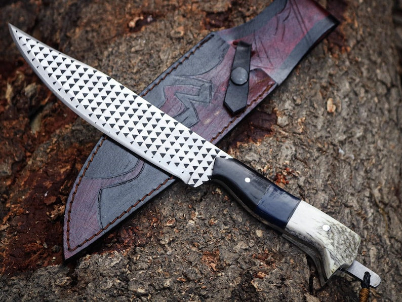 Decorative knife with a textured blade and leather sheath on a textured surface