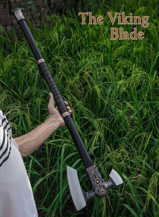 Person holding a decorative axe with 'The Viking Blade' text against a grassy background