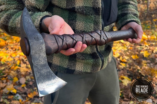 Hand-forged Gurons spike tomahawk with a steel head and an ashwood handle, held in a hand with a leather cover on the handle.