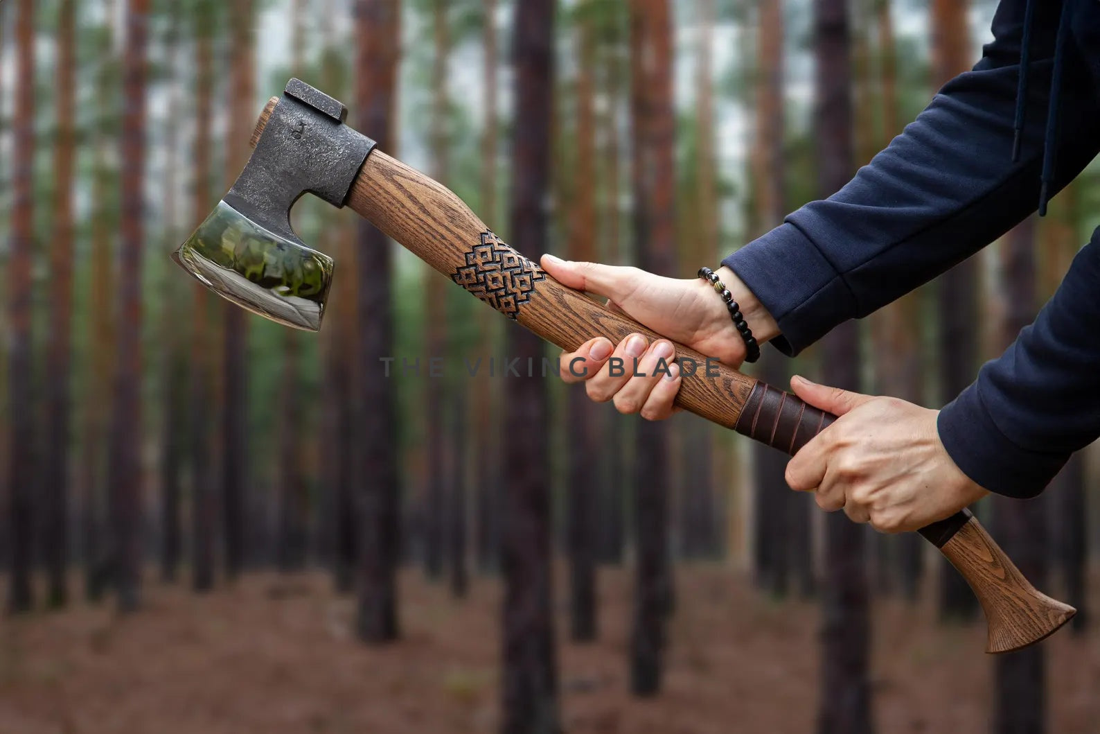 Person holding a wooden-handled axe in a forest setting