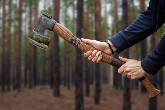 Person holding a wooden-handled axe in a forest setting