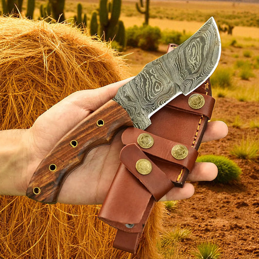 Hand holding a knife with a wooden handle and leather sheath against a desert background