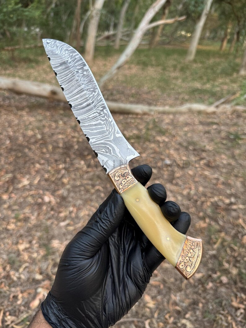 Decorative knife with a decorative handle held by a gloved hand against a natural background.