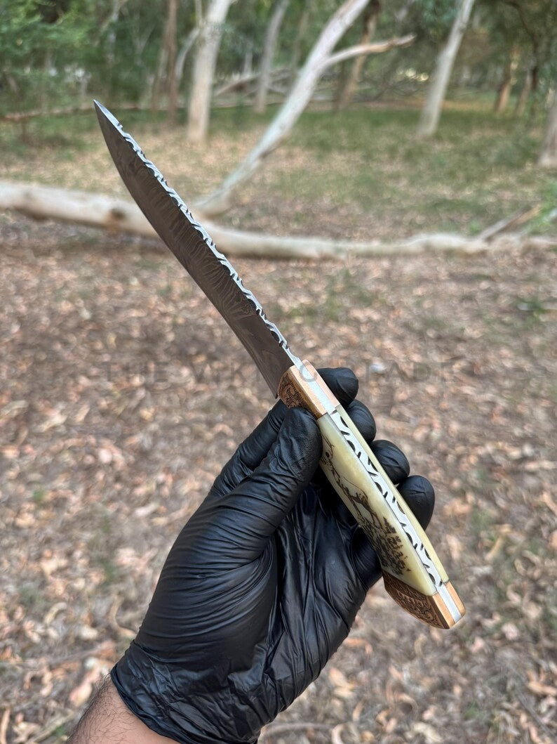 Knife with a wooden handle held by a gloved hand against a natural background