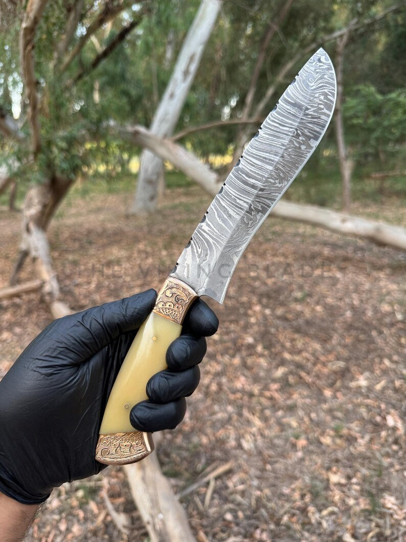 Knife with decorative handle held by a person wearing black gloves, outdoors.