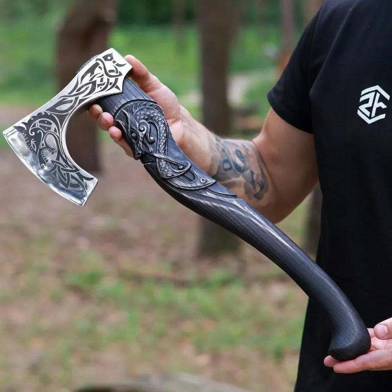 Person holding a decorative axe with intricate designs outdoors