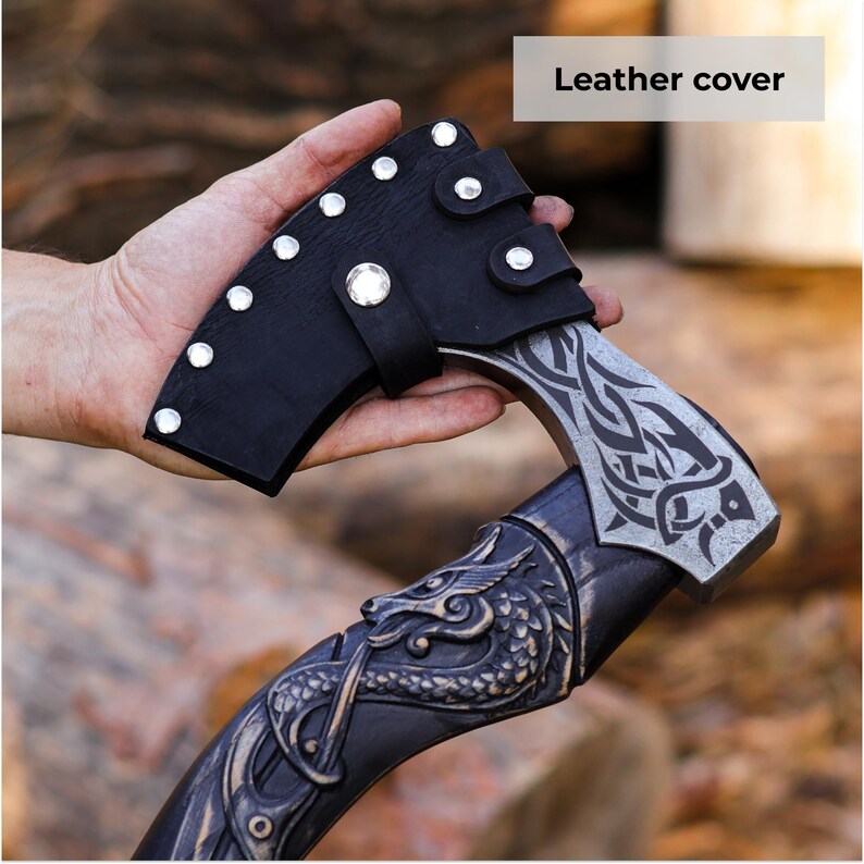 Hand holding a decorative axe with a leather cover against a natural background