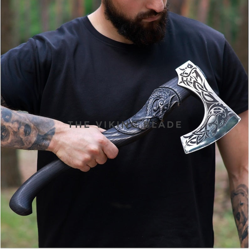 Man holding a decorative axe with intricate designs, wearing a black t-shirt.
