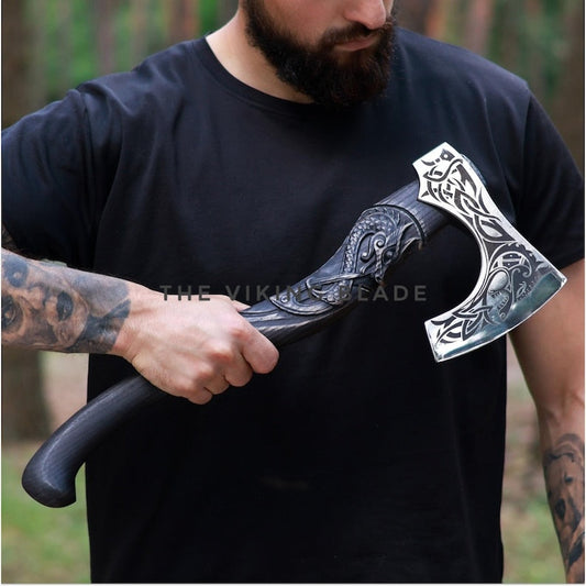 Man holding a decorative axe with intricate designs, wearing a black t-shirt.