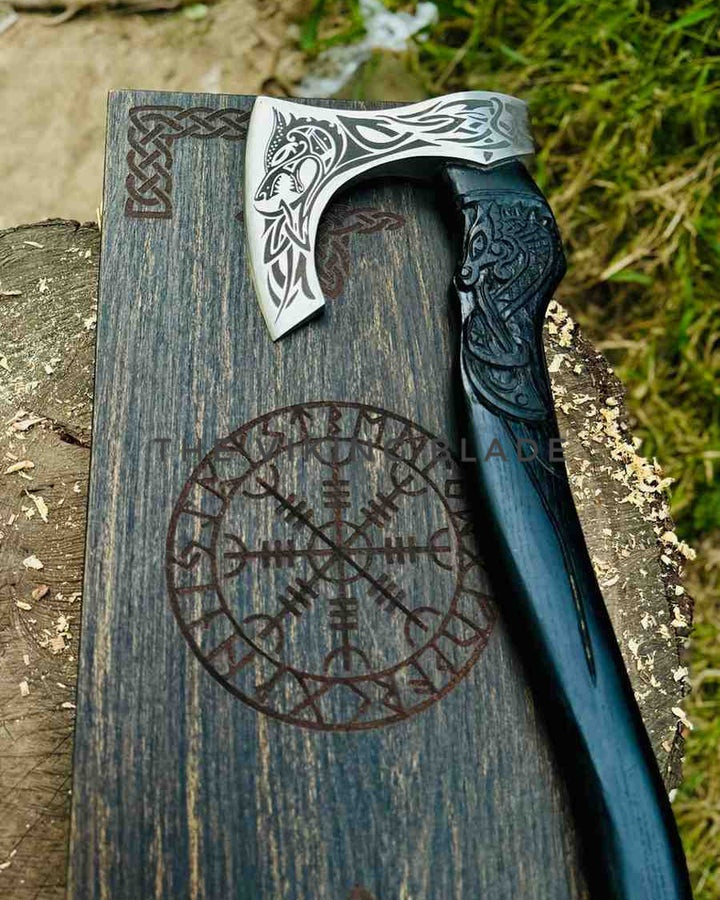 Decorative axe with intricate designs on a wooden block with engraved symbols, outdoors.
