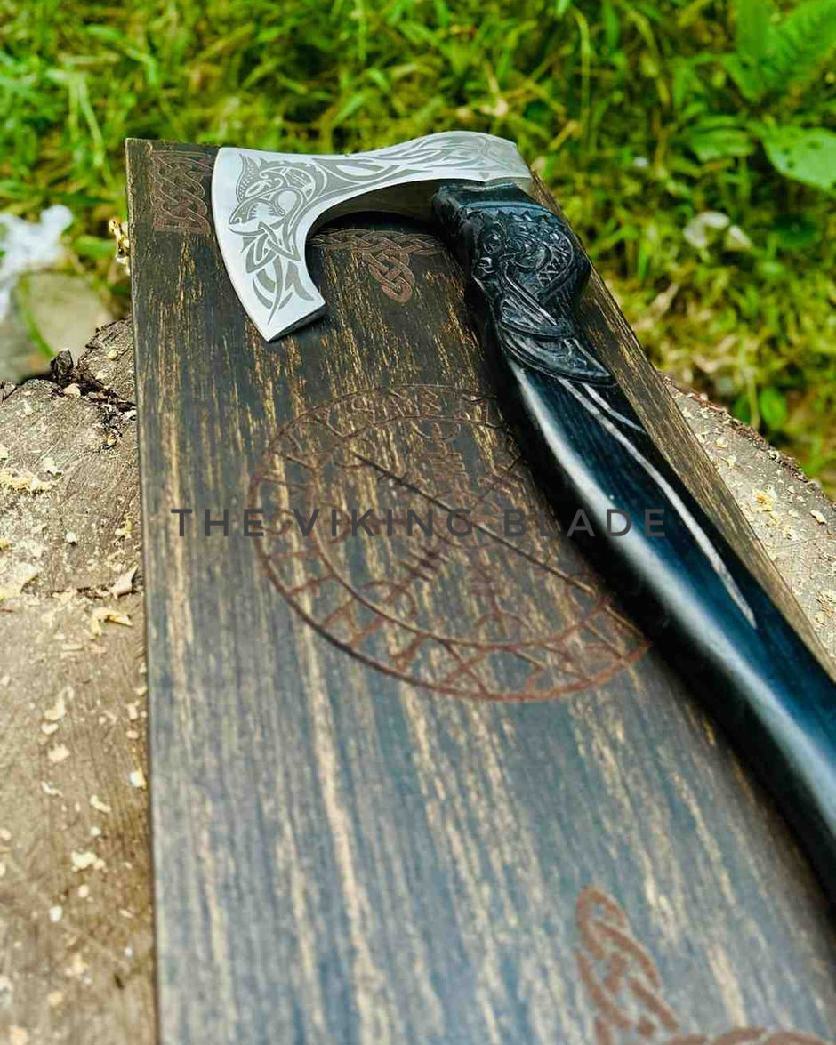 Decorative axe with engraved handle on a wooden surface, branded 'The Viking Blade'.