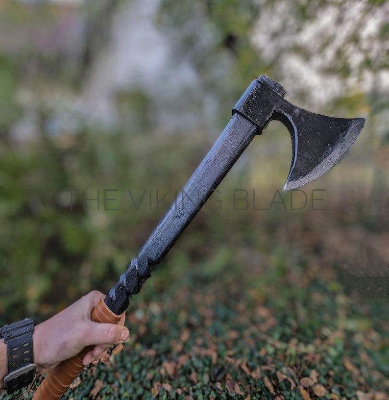 Person holding a Viking-style axe with a blurred natural background