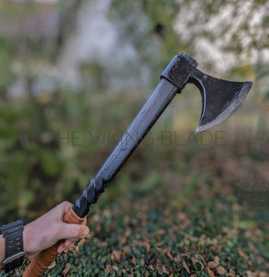 Person holding a Viking-style axe with a blurred natural background