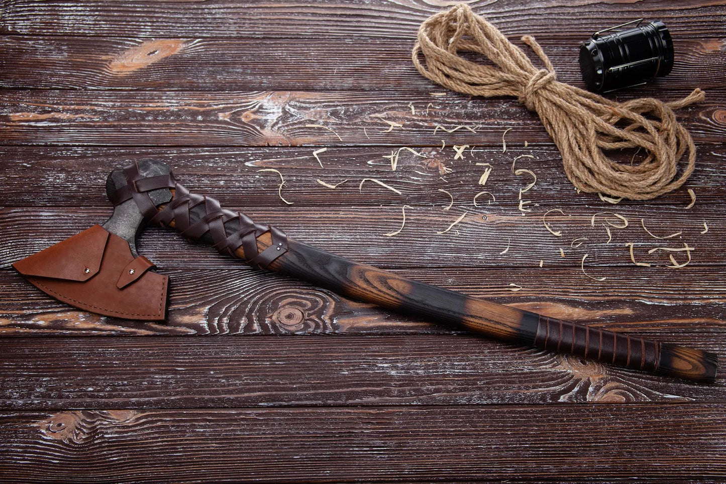 Decorative axe with leather sheath and rope on a wooden surface