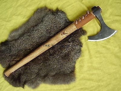Wooden-handled axe on a fur surface with a green background