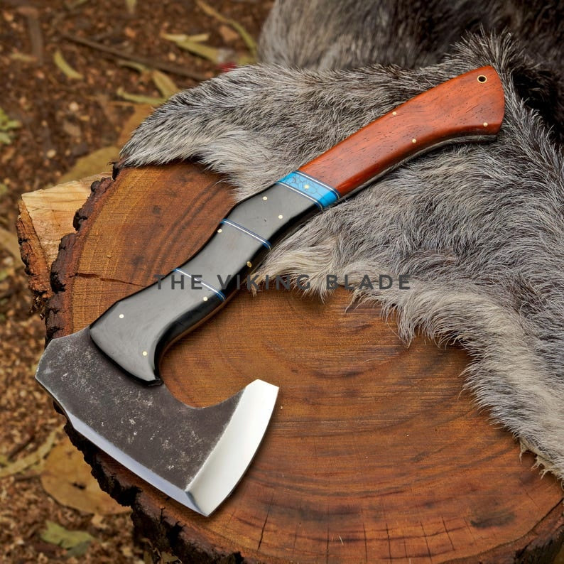 Axes with wooden handles on a log, branded 'The Viking Blade'.