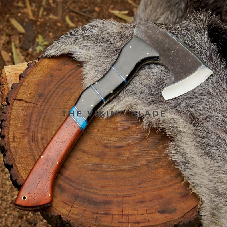 Axes with wooden handles on a wooden surface, branded 'The Viking Blade'.