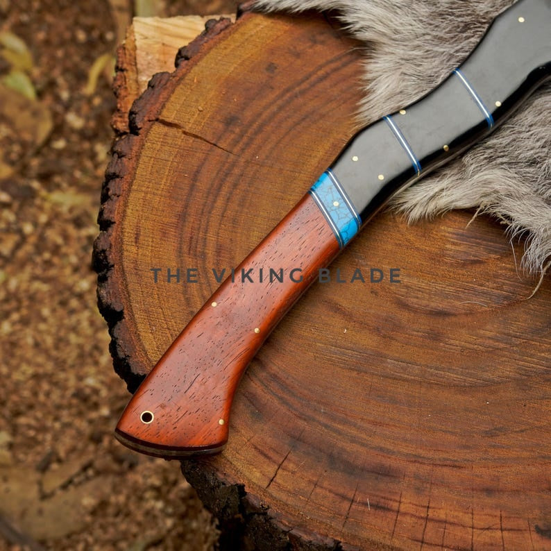 Knife with wooden handle and blue accent on a wooden surface, branded 'The Viking Blade'.