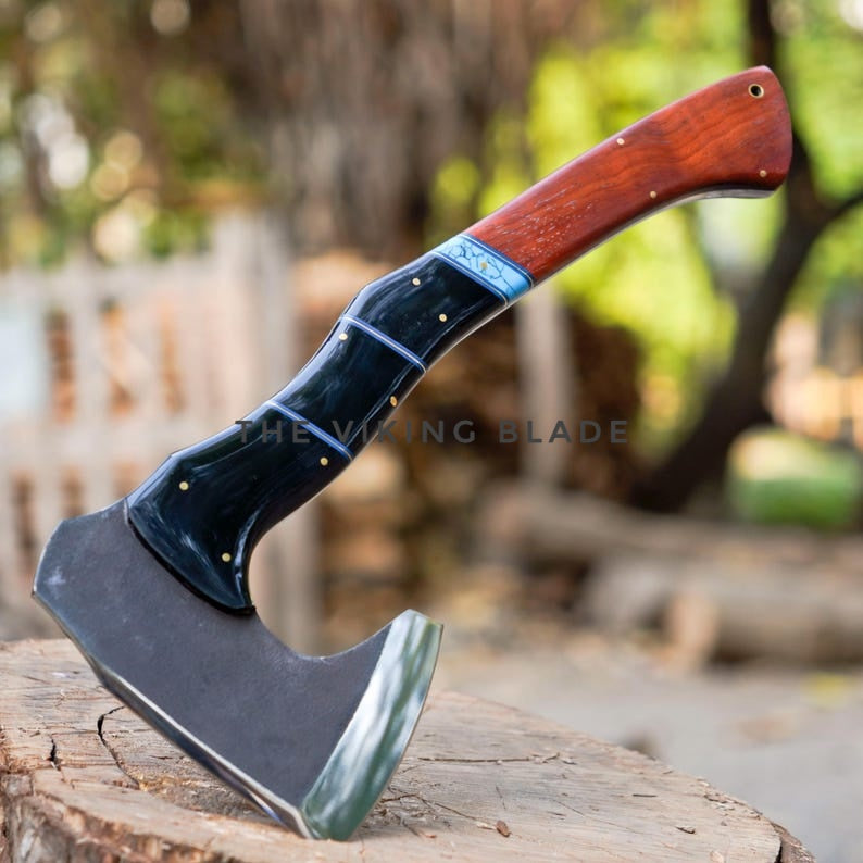 Axes with wooden handles on a log, blurred natural background