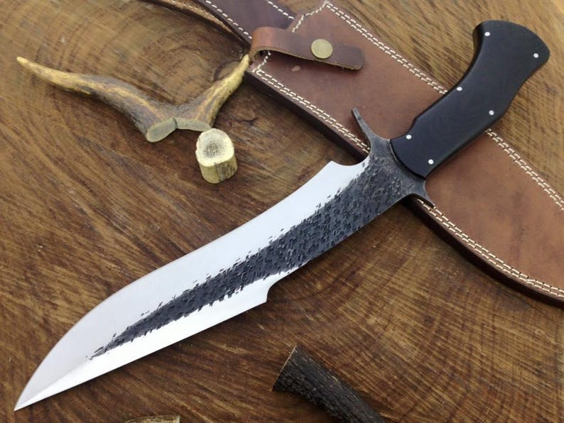 Forked spearhead knife with black handle on a wooden surface
