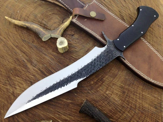 Forked spearhead knife with black handle on a wooden surface