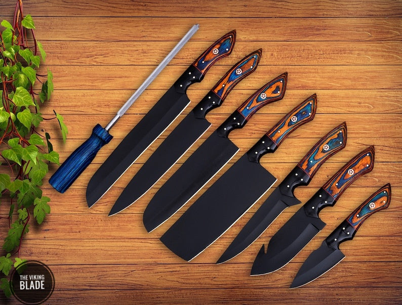 A set of handmade chef knives with black blades and wooden handles, accompanied by a leather sheath roll, displayed on a wooden surface.